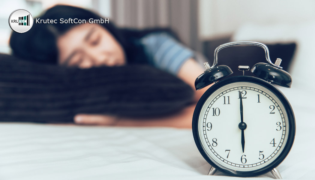 Verschwommene Frau schlafend im Hintergrund hinter einem analogen Wecker